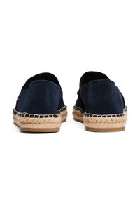 Alpargatas de ante azul marino con suelas de yute; presentan detalles de costura y un pequeño logo en el costado. Estilo slip-on con parte trasera redondeada.