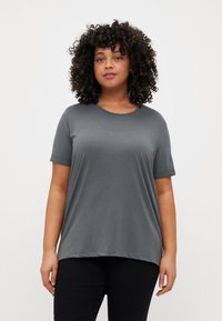 Gray short-sleeve T-shirt with a round neckline, soft fabric, relaxed fit, and rolled cuffs, paired with dark trousers.
