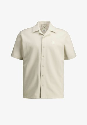 Chemise boutonnée à manches courtes de couleur crème avec tissu texturé et col pointu, présentée sur un fond blanc.