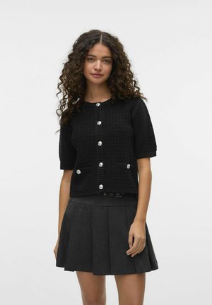 Cardigan noir à manches courtes en tissu tricoté texturé, avec des boutons ronds en argent, deux poches avant et une coupe décontractée.