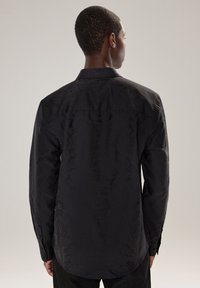 Camicia nera a maniche lunghe con un sottile motivo floreale in rilievo, polsini con bottoni e colletto classico. Tessuto liscio con finitura opaca.