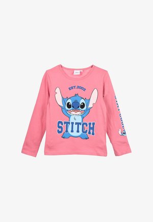 Roze langemouwen shirt met een blauwe cartoonfiguur met omhoog gestoken armen, "EST.2002" erboven en "STITCH" in vetgedrukte blauwe letters.