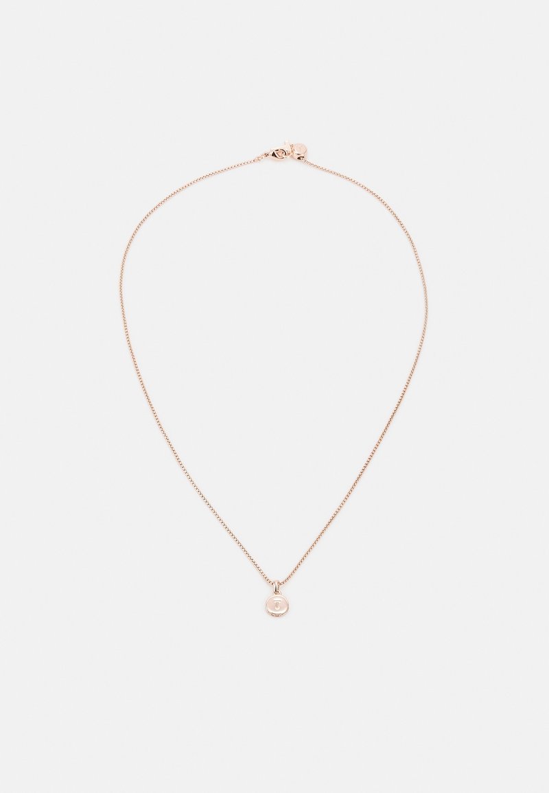 Collier délicat en chaîne en or rose avec un petit pendentif rond gravé de la lettre T, posé à plat sur un fond blanc.