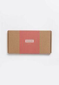 Bruine kartonnen doos met een roze label waarop het woord "SNOCKS" en "SLIP" in het wit is gedrukt. Gladde textuur, rechthoekige vorm.