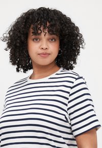 T-shirt à rayures blanches et marine à manches courtes avec un col rond, offrant une coupe décontractée et une texture de tissu douce et lisse.