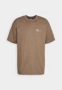 T-shirt marron à manches courtes, col rond, avec un petit texte blanc sur la partie haute gauche de la poitrine mentionnant « DRDENIM, Gothenburg, Sweden. »