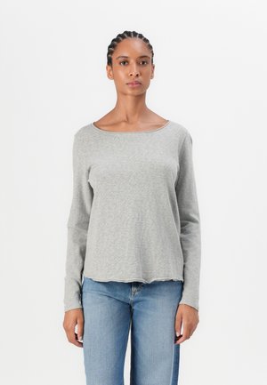 Gray long-sleeve top with a scoop neckline. Made of a soft, textured fabric with a slightly curved hem. Paired with blue denim jeans.