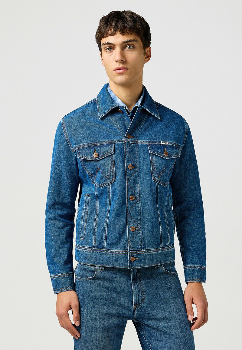 Jeansjacka i medelblå med en klassisk design, som har två bröstfickor, bruna knappar och en spetsig krage. Strukturerat tyg.