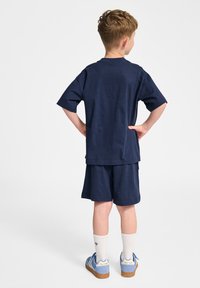Marinblå bomulls t-shirt och shorts set, avslappnad passform, korta ärmar, med matchande strumpor och ljusblå sneakers. Enkelt mönster, utan mönster.