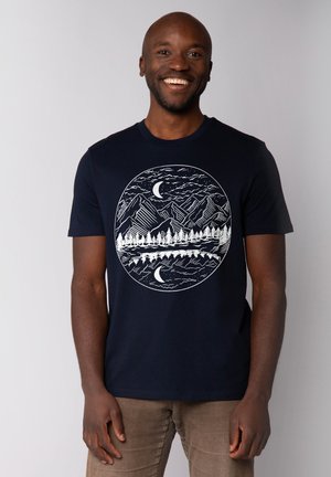 Marineblauw t-shirt met een witte cirkelvormige afbeelding van bergen, bomen en manen. Korte mouwen, ronde halslijn, van katoen.