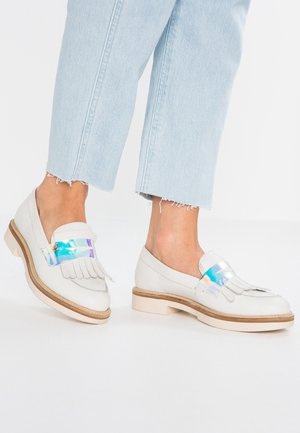 Weiße Leder-Loafer mit Fransen-Design und holografischem Schnallendetail. Sie verfügen über eine klobige Sohle und beige Akzente.