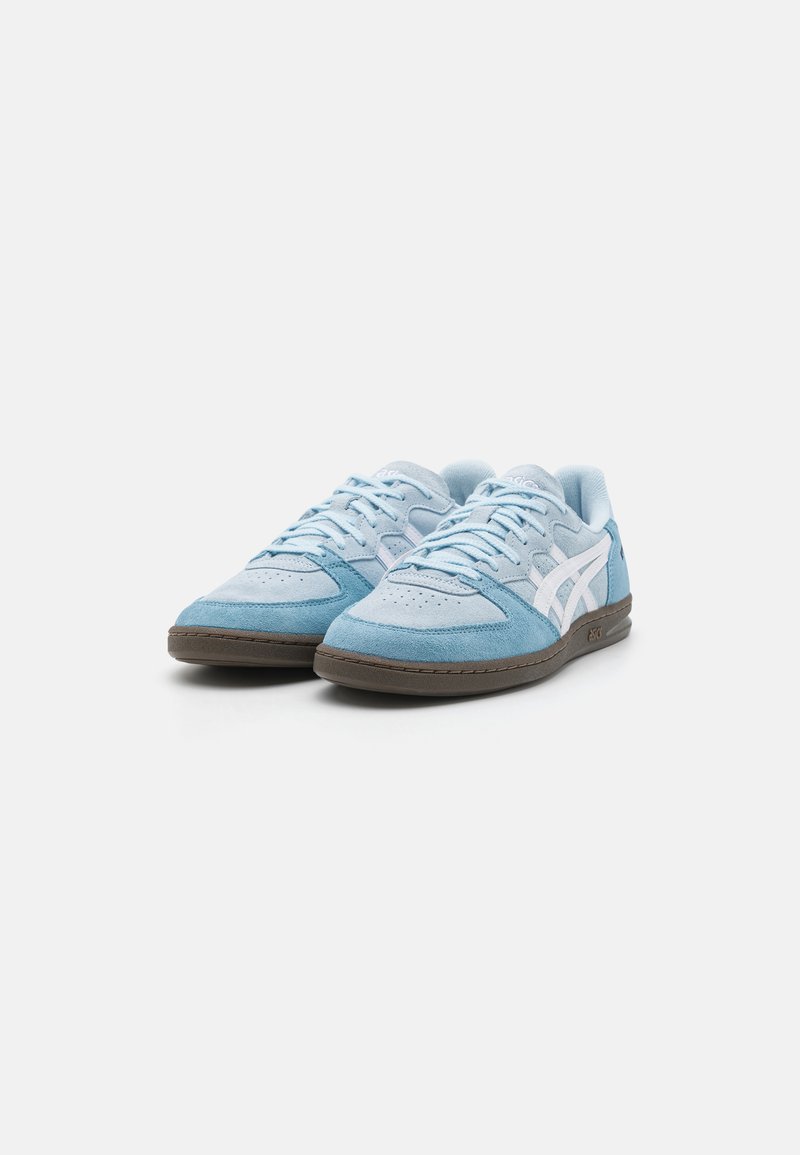 Zapatillas de ante azul claro con detalles en blanco, cordones redondos y suela de goma marrón. Presentan perforaciones en la puntera para mayor transpirabilidad.