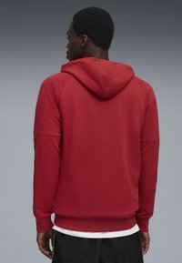 Rød hættebluse med ribbet cuffs og kant, med et ensfarvet design. Materialet ser blødt ud med en afslappet pasform.
