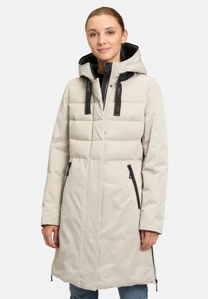 Cappotto puffer beige chiaro con cappuccio strutturato, accessori neri, due cerniere laterali e un motivo trapuntato sulla parte superiore.