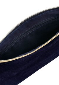 Marinblå mockapåse med ett guld dragkedja, med en mjuk textur och ett rymligt inre. Insidan är fodrad med svart tyg.