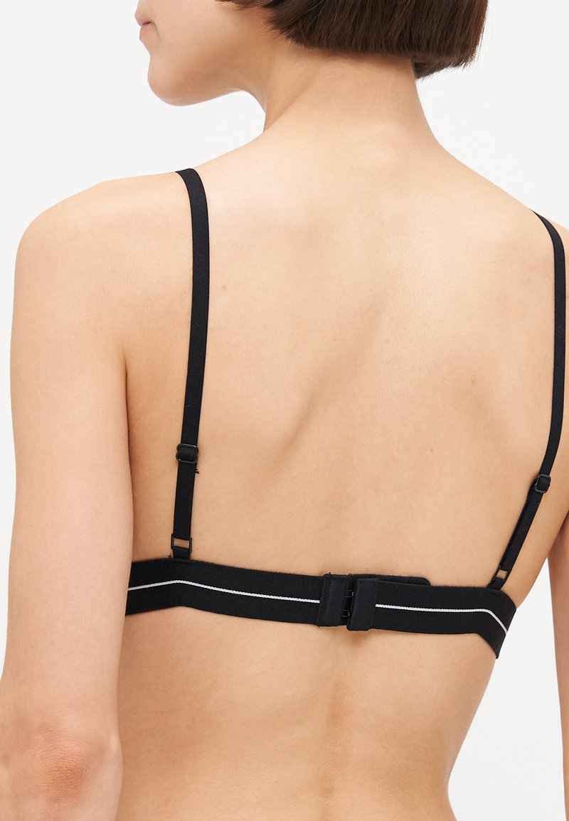 Sostenedor negro con tirantes ajustables, cierre de gancho y una franja blanca contrastante a lo largo de la banda. Tela suave y diseño minimalista.