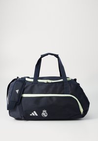 Marine duffel taske lavet af slidstærkt stof, med lysegrønne lynlåse, bærehåndtag, justerbar rem og logoet fra Real Madrid.
