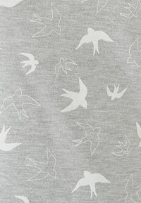 Tejido gris que presenta un patrón repetido de pájaros blancos en varias posiciones de vuelo. Textura suave con un sutil aspecto jaspeado.
