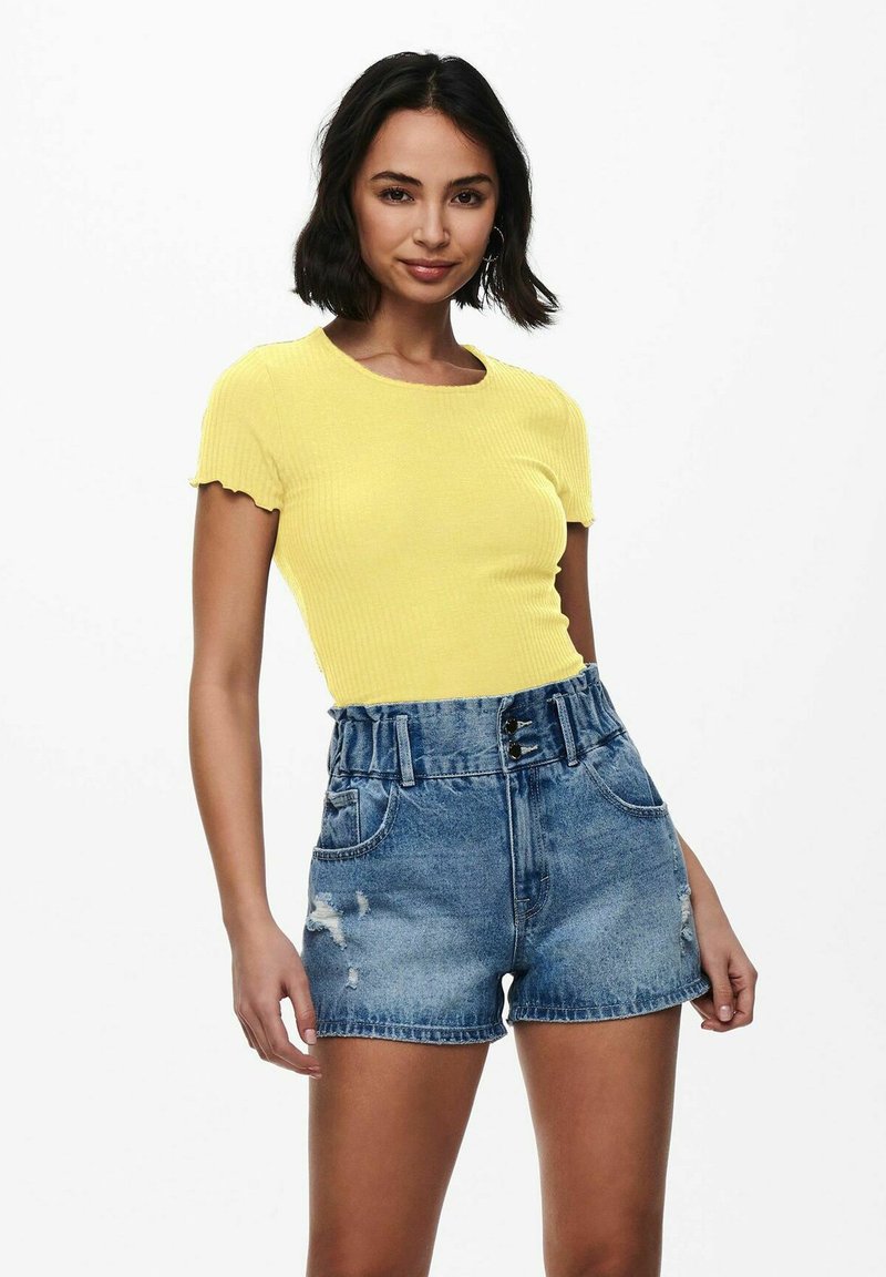 Gelbes geripptes Croptop und ausgefranste, hochtaillierte Denim-Shorts. Das Top hat kurze Ärmel und einen runden Ausschnitt; die Shorts haben einen taillierten Bund mit einem Gürtel.