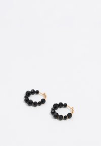 Boucles d'oreilles en forme de créole noires avec des perles facettées et un fermoir en ton doré, de forme circulaire, avec une texture lisse et une finition polie.