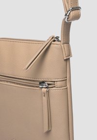 Borsa a spalla in pelle beige con superficie tessurizzata, dotata di un compartimento principale con zip e una tasca frontale con zip e dettagli decorativi in frangia.