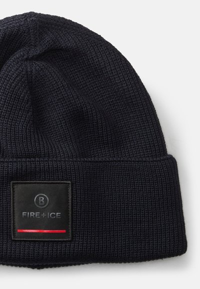 Gorro de malha em azul marinho escuro com um padrão texturizado, apresentando um retângulo preto com um logótipo e uma linha de destaque vermelha na parte inferior.