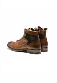 Bottines en cuir marron avec des accents en daim foncé, bout rond, finition légèrement texturée et design à lacets. Présente un logo visible sur le côté.