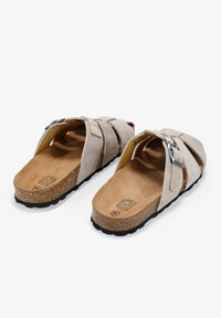 Sandalias de ante en color beige, con correas cruzadas y una hebilla de metal plateado, sobre una suela ligera de corcho y goma.