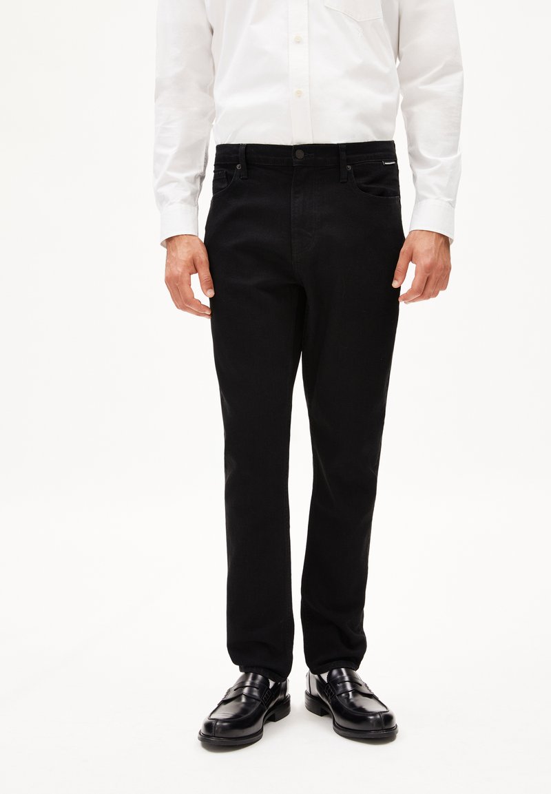 Zwarte denim jeans met een rechte snit, vijf zakken ontwerp en een sluiting met knoop aan de voorkant, gecombineerd met een wit overhemd en zwarte schoenen.