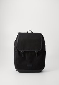 Black fabric backpack featuring a flap closure, two front straps, side pockets, and a textured finish with a leather bottom accent.