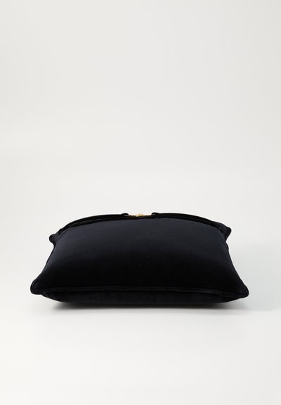 Svart sammetspål med rektangulär form, utrustad med en guldfärgad hårdvarudetalj på toppen och kantad med pipade kanter för en färdig look.