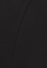 Svart tyg med en slät, något strukturerad yta, som visar en enhetlig färg och jämn sömnad. Inga mönster eller accentuerade detaljer finns.