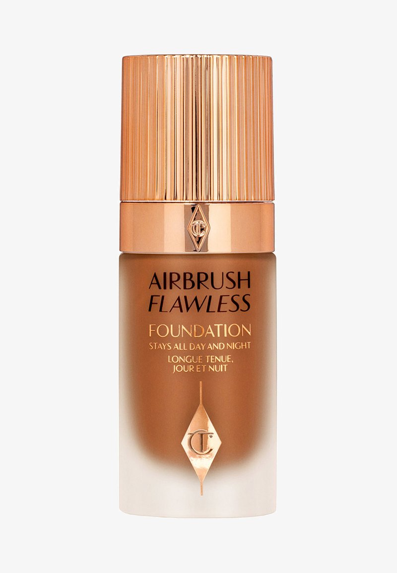 Airbrush Flawless Foundation in a cylindrical glass bottle. Features a gold ribbed cap, gradient amber to white finish, and embossed logo.