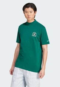 Green short-sleeve t-shirt with a high collar, featuring a white graphic logo on the chest and a small logo on the sleeve. Cotton material.