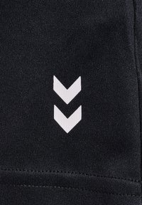 Svart tyg har en vit chevron-logotypdesign. Texturen verkar slät, med synlig sömnad i den nedersta kanten.