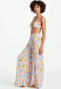 Blumiger zwei-teiliges Badeanzugset bestehend aus einem Bralette mit dünnen Trägern und weiten Hosen, aus leichtem, gemustertem Stoff in Pastellfarben.