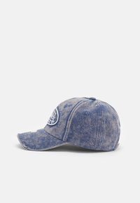 Denim kapa z ukrivljenim vizirjem, bledmodre barve, izvezena logotipna nalepka spredaj in obrabljeni detajli ob robovih.