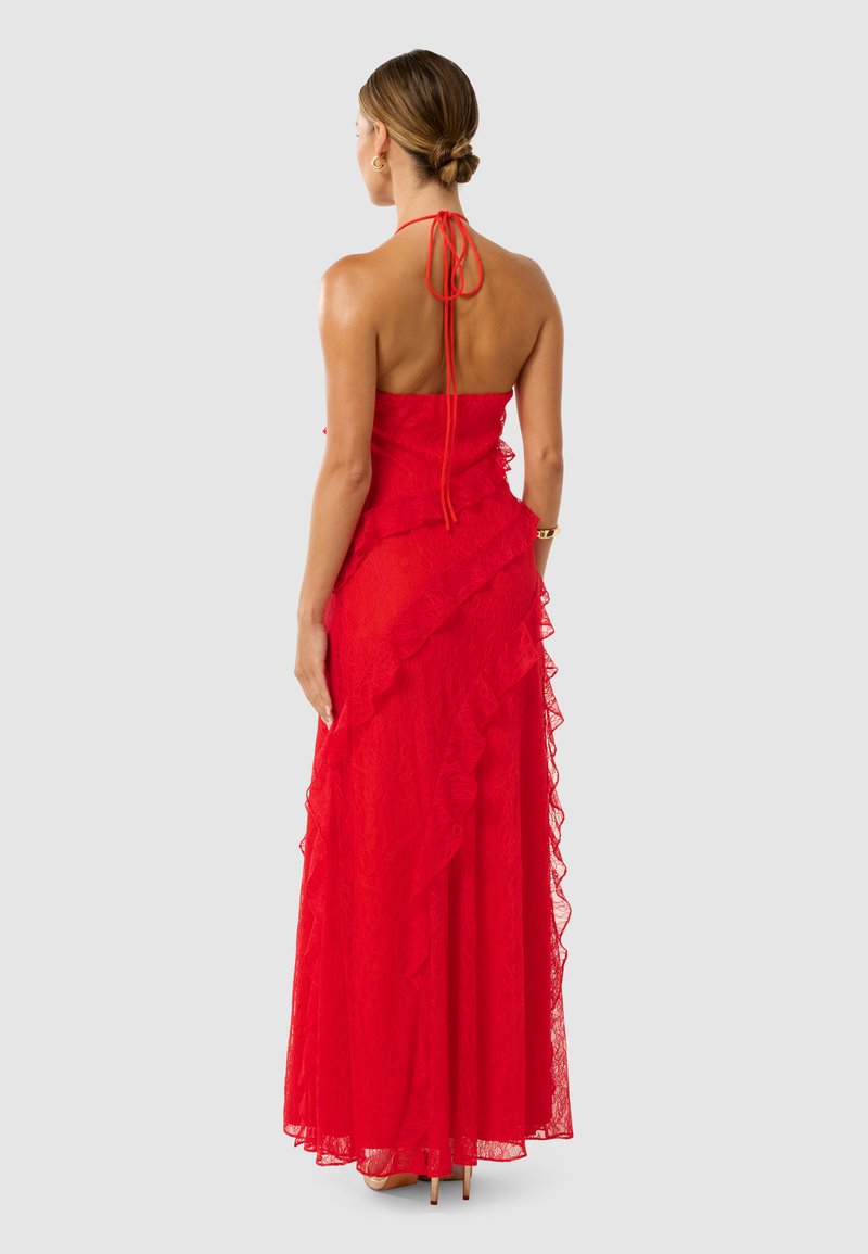 Robe maxi en dentelle rouge avec un buste ajusté, des couches froncées et un lien halter avec un dos ouvert. Tissu lisse et texturé qui tombe élégamment.