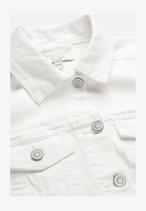 Witte spijkerjasje met metalen drukknopen en puntige kraag, met binnenin de kraag het label "Cellbes of Sweden" maat 38/40 zichtbaar.