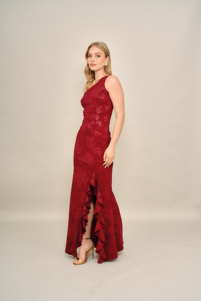 Rode avondjurk met bloemenpatroon, één schouderriem, aangesloten lijfje en geplooide zoom, gecombineerd met gouden sandalen met hak.