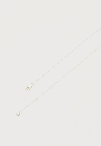 Collier à chaîne fine en argent avec fermoir mousqueton et petites étiquettes rondes sur un fond blanc uni.