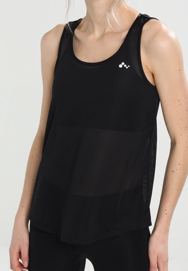 Femme portant un débardeur de sport noir en mesh sans manches avec un petit logo blanc sur la poitrine gauche sur un fond clair uni.