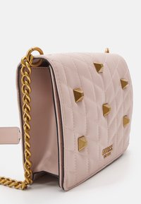 Prošívaná růžová syntetická kabelka s pozlacenými pyramidovými cvoky, zlatým řetízkovým páskem a vyraženým logem značky na přední straně.
