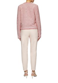 Rood en witte textuurjack met lange mouwen, ronde halslijn en een cropped fit, gecombineerd met lichtbeige op maat gemaakte broeken en sandalen met bandjes.