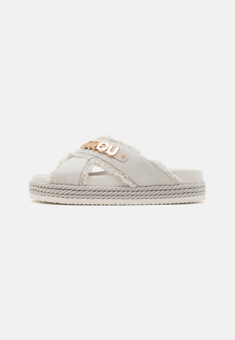 Slide sandal in light gray fabric with frayed edges, featuring a gold-tone metal accent and a braided jute midsole. Soft-textured footbed.