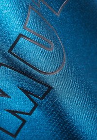 Textil i levande blått med en slät, glänsande yta, prydd med djärva svarta bokstäver och ett subtilt ribbat mönster.