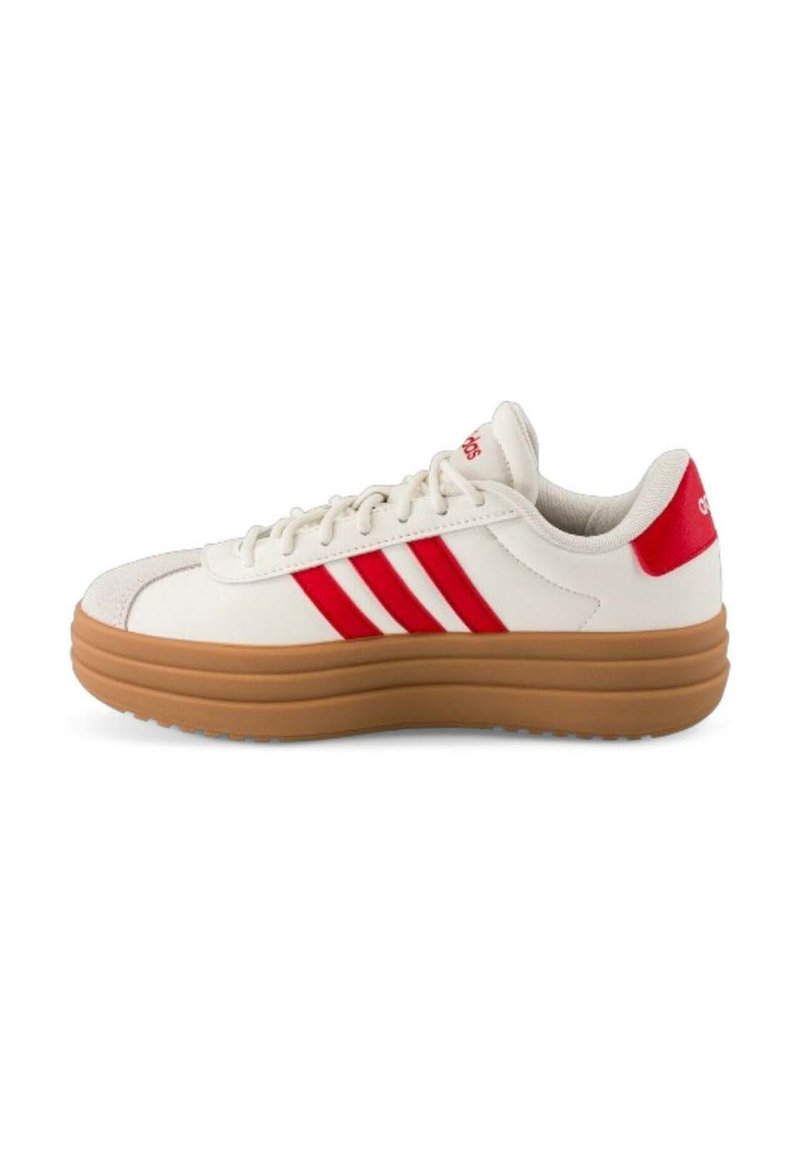 Sneakers bianchi con tre strisce rosse, suola in gomma testurizzata e collare imbottito, caratterizzati da una tomaia in pelle liscia e dettagli minimi.