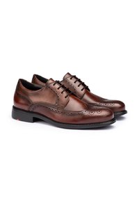 Scarpe in pelle marrone con lacci, caratterizzate da dettagli brogue, punta tonda e suola in gomma nera testurizzata per una migliore aderenza.