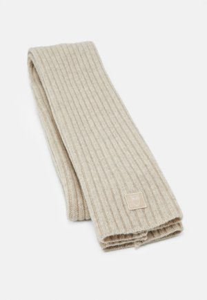 Beige geribbelde gebreide sjaal, gevouwen met een klein vierkant stoffen label met een eenvoudig uil-logo aan één uiteinde.