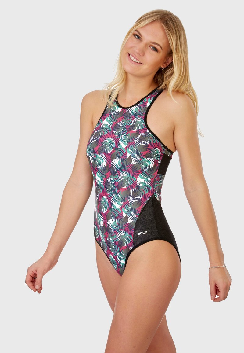 Le maillot de bain présente un motif de feuilles de palmier multicolore avec un panneau latéral noir. Il a un col montant et un design dos nageur. Le matériau semble lisse.
